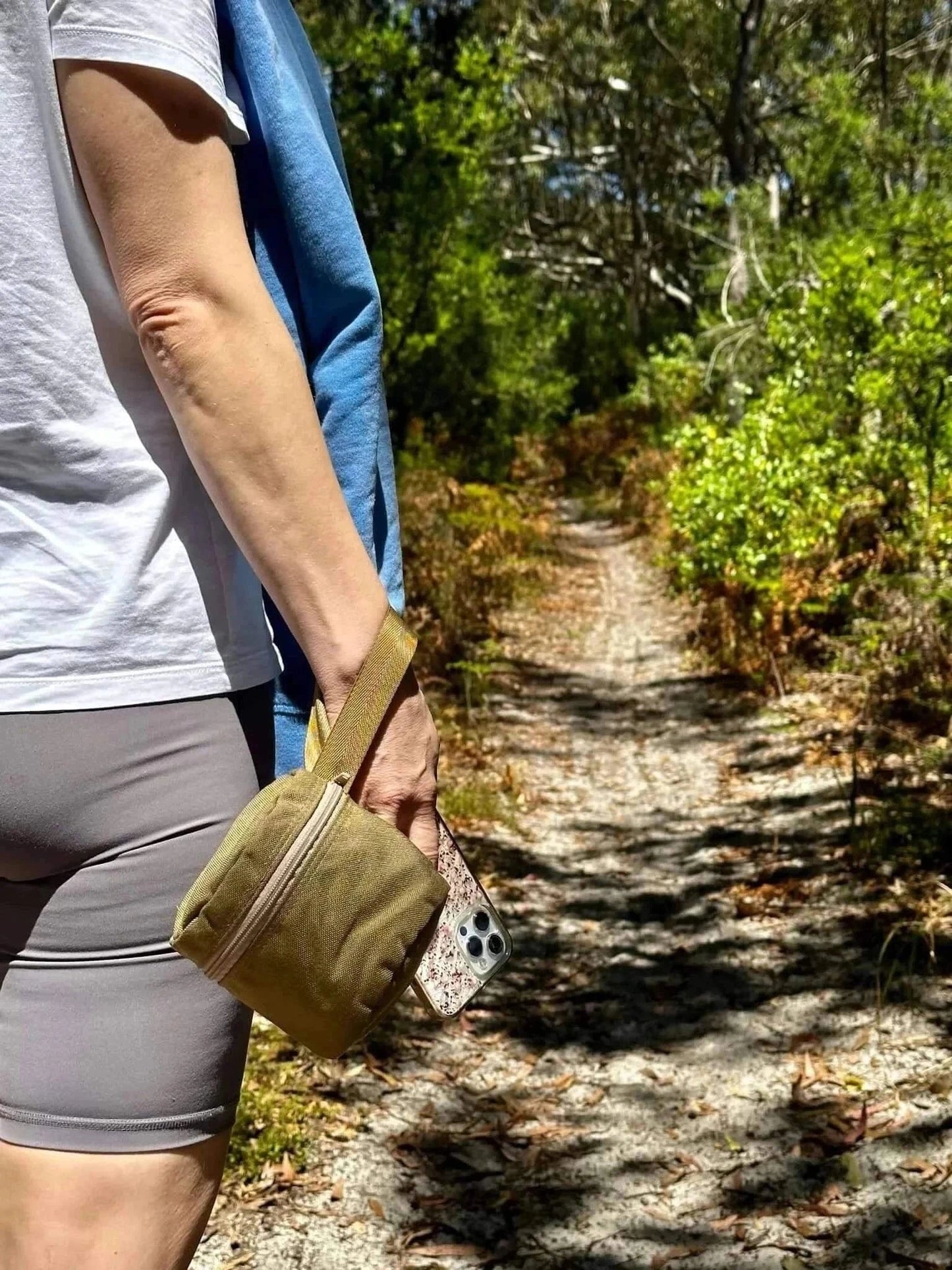 Portable toilet roll holder with wristband, ideal for outdoor adventures, shown on a hiking trail.