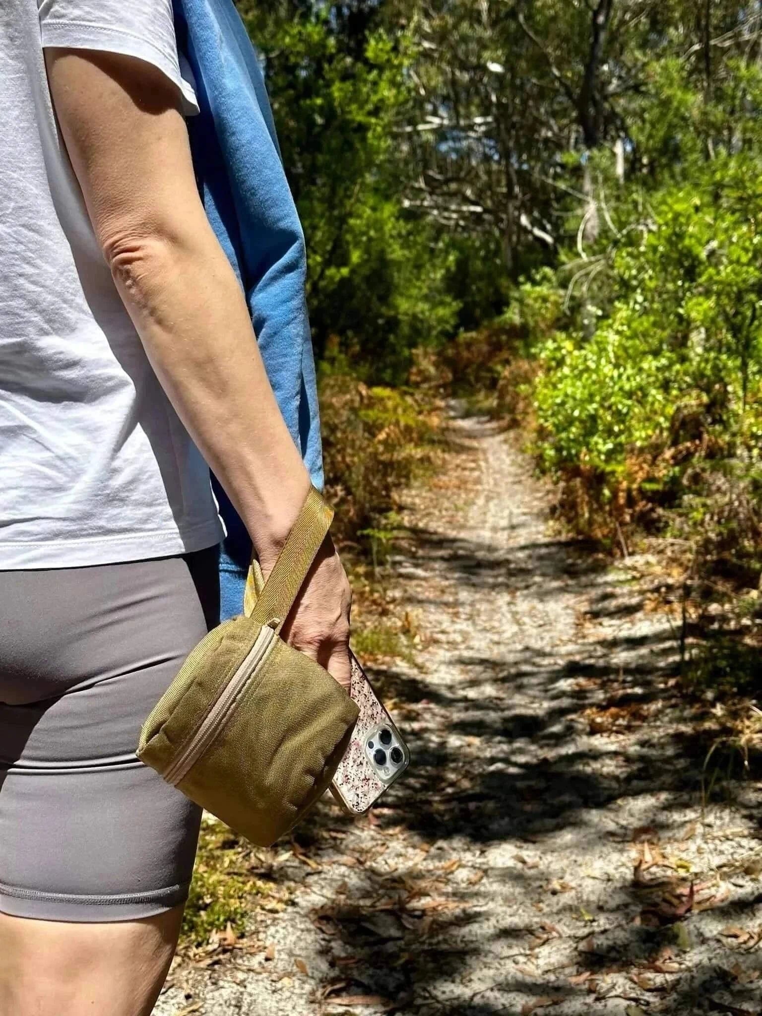 Portable toilet roll holder with wristband, ideal for outdoor adventures, shown on a hiking trail.