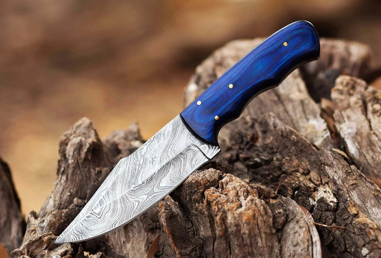 Damascus Steel Hunting Knife with Pakka Wood handle, resting on wood.