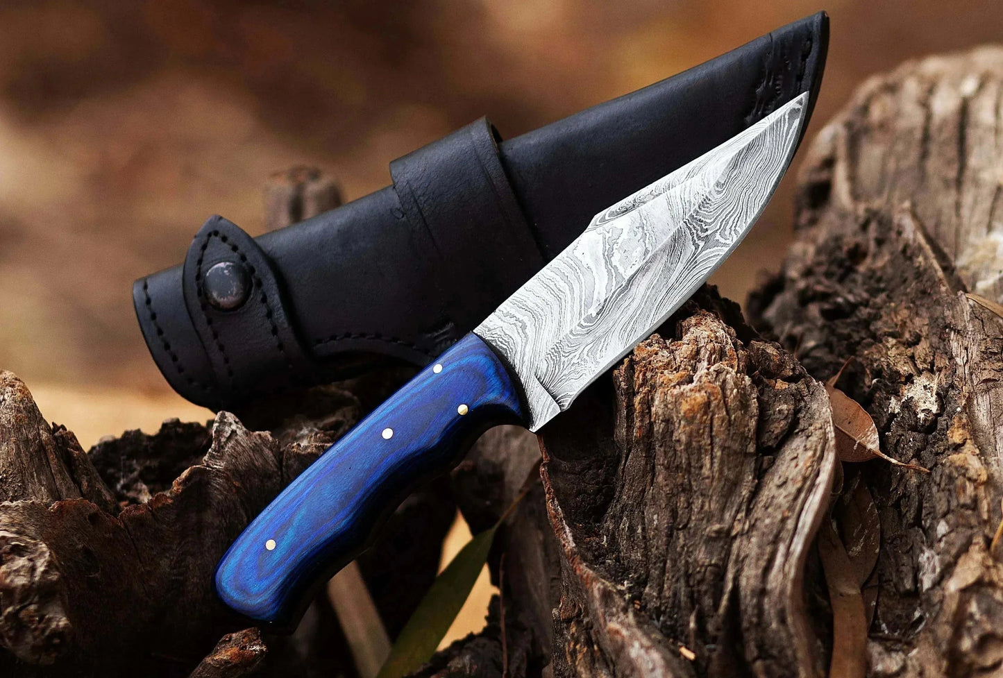 Damascus Steel Hunting Knife with Pakka Wood handle and premium leather sheath on a wooden log background.