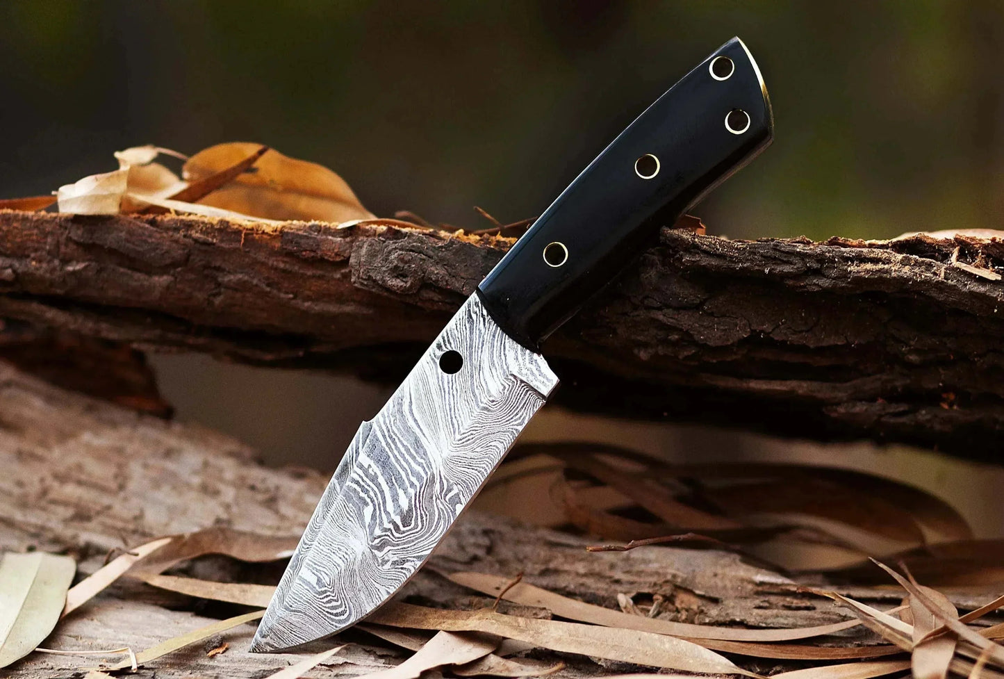 Damascus Steel Hunting Knife with bull horn handle, displayed outdoors.
