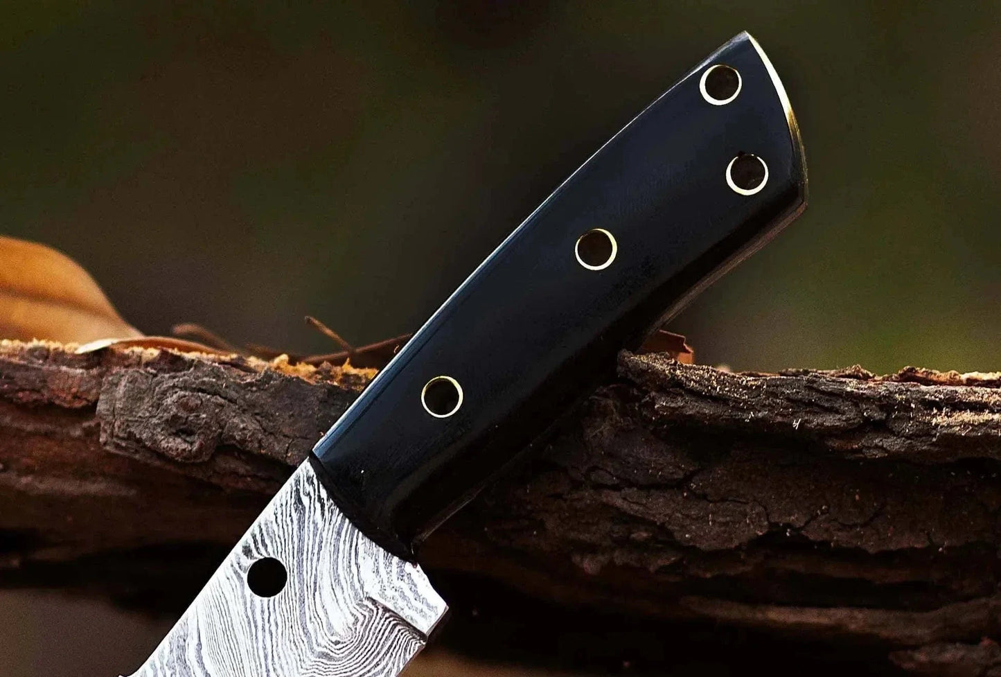 Damascus Steel Hunting Knife with bull horn handle on wood surface.