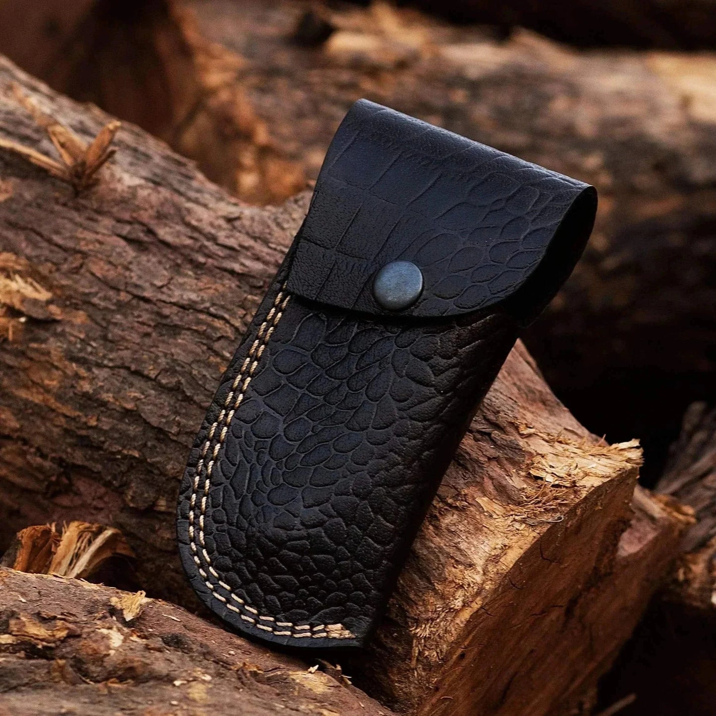Crocodile leather sheath for Damascus Steel Folding Knife on wooden background.