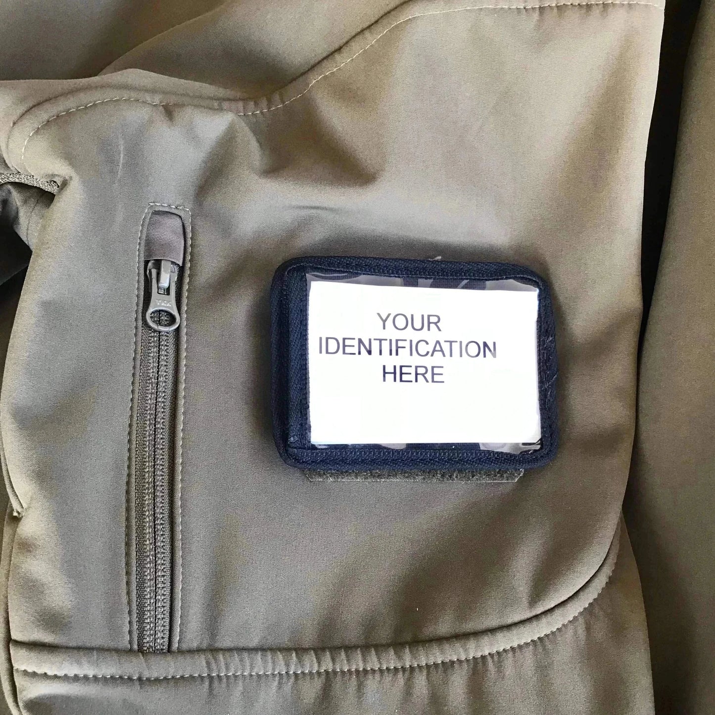 Velcro ID card holder attached to a uniform with a clear window displaying an identification card.