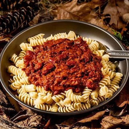 Vegan bean bolognese served with pasta in an outdoor setting, ideal for hiking and camping.