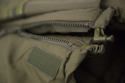 Close-up of Carinthia Defence 4 sleeping bag zipper, showcasing its robust construction and olive color fabric for ultimate cold-weather performance.