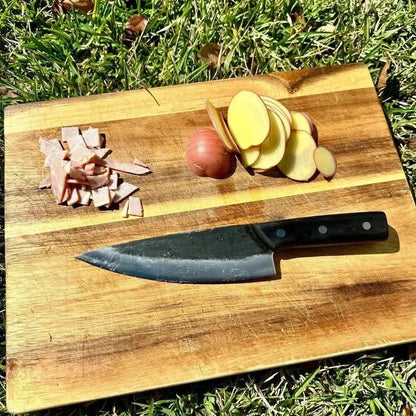 Camping knives on a wooden board with sliced potatoes and onions, showcasing a reliable camping cooking set.