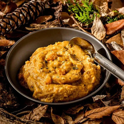 Herb-Infused Pumpkin and Potato Mash in a bowl surrounded by autumn leaves, ideal hiking food.