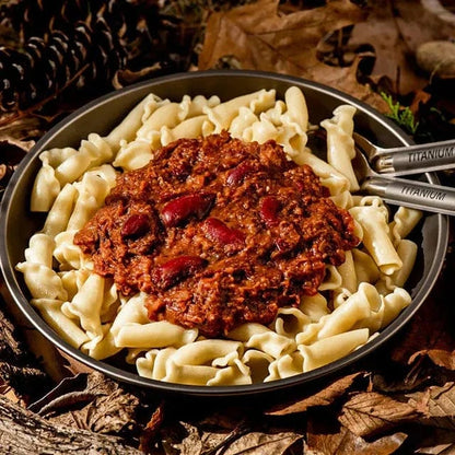 Mild Chilli Con Carne with beans and beef over pasta on a rustic outdoor setting.
