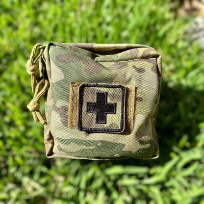 Tactical First Aid Kit in Multicam fabric with black cross patch, durable and portable for emergencies.
