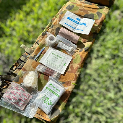 Tactical First Aid Kit with essential medical supplies in military-grade pouch on grass background.