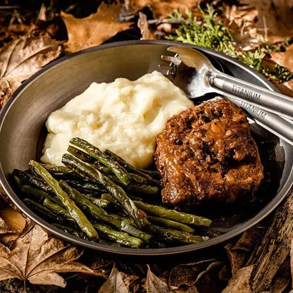 Slow-cooked Australian steak in peppery gravy with mashed potatoes and green beans on a plate.
