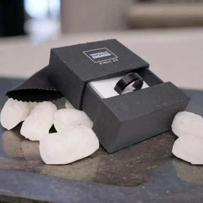 Beveled Tungsten Ring in black velvet box with cleaning cloth on a table, showcasing modern elegance and durability.