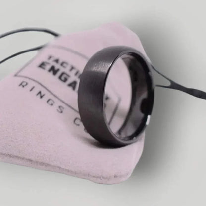 Matte black tungsten ring on a soft pouch, showcasing its sleek and durable design.