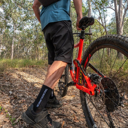 Cyclist wearing TacSource Active Train 2.0 Socks on a mountain trail.