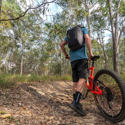 Man mountain biking through forest trail wearing TacSource Active Train 2.0 Socks.