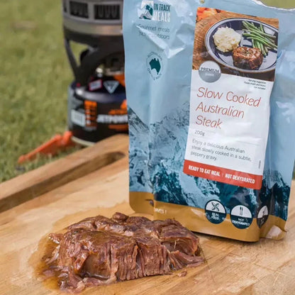 Slow-cooked Australian steak in peppery gravy packaging on a wooden board with steak.