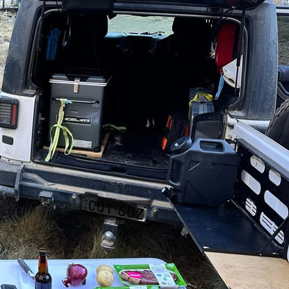 Ultimate Portable Water Container for camping in a car with supplies nearby.