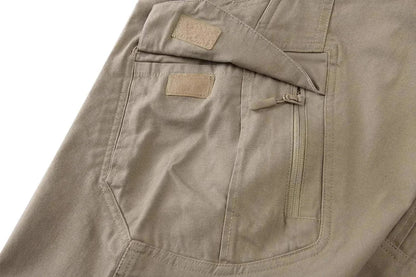 Close-up of khaki tactical pants with multiple pockets and zipper detail.