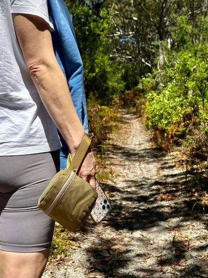Portable toilet roll holder with wristband, ideal for outdoor adventures, shown on a hiking trail.