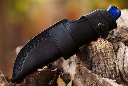 Damascus Steel Hunting Knife with leather sheath on wood background.