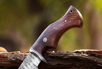 Damascus Steel Hunting Knife with rosewood handle displayed outdoors.