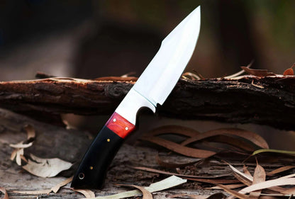 High Carbon Steel Hunting Knife with leather sheath and bull horn handle on a log outdoors.