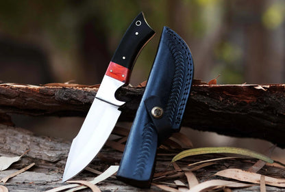 High carbon steel hunting knife with leather sheath on wood background.