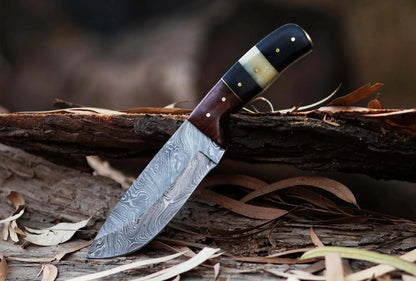 Damascus Steel Hunting Knife with Pakka Wood handle on a rustic surface.