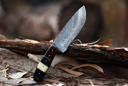 Damascus Steel Hunting Knife with textured blade and wooden handle resting on bark.