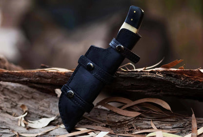 Damascus Steel Hunting Knife with leather sheath on wood background.