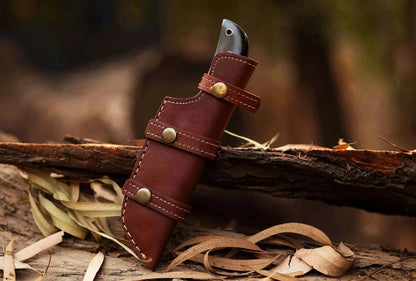 Damascus Steel Hunting Knife with leather sheath on wood.
