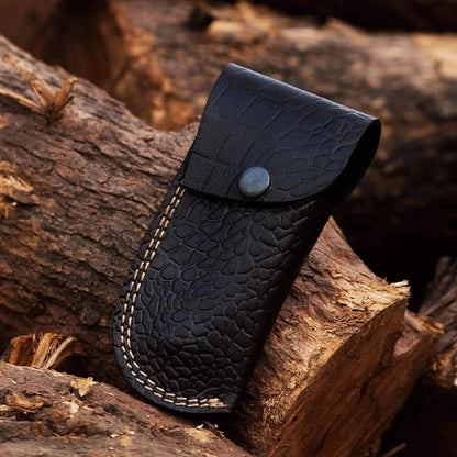 Crocodile leather sheath for Damascus Steel Folding Knife on rustic wood background.