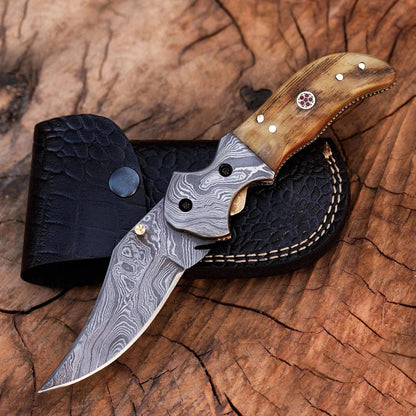 Damascus Steel Folding Knife with Crocodile Leather Sheath on Wooden Surface