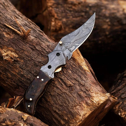 Damascus Steel Folding Knife with Ram Black Horn handle on wooden background, showcasing intricate Damascus pattern and craftsmanship.