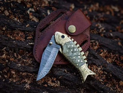 Fish style Damascus steel folding knife with leather sheath, featuring intricate handle design and layered blade pattern.