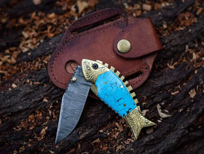 Fish Style Damascus Steel Folding Knife with leather sheath, featuring a unique fish design, blue handle, and distinctive blade pattern.