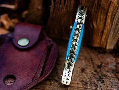 Fish Style Damascus Steel Folding Knife with leather sheath on wood background.