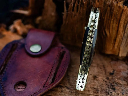 Fish Style Damascus Steel Folding Knife with leather sheath on wooden background.