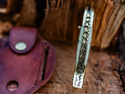 Fish Style Damascus Steel Folding Knife with leather sheath on wooden background.