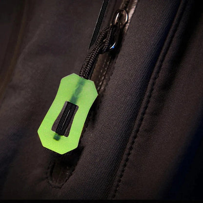 Glow-in-the-dark zipper pull on a black fabric surface, enhancing nighttime visibility and safety for outdoor gear.