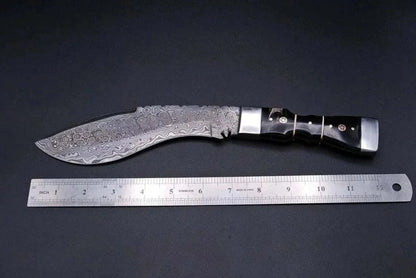 Damascus Steel Kukri Knife with patterned blade and black handle, next to a measuring ruler.
